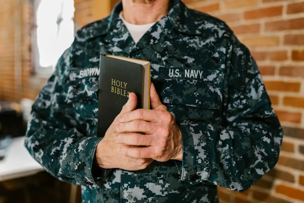 A U.S. Navy sailor in uniform holding a Holy Bible, symbolizing faith and service.